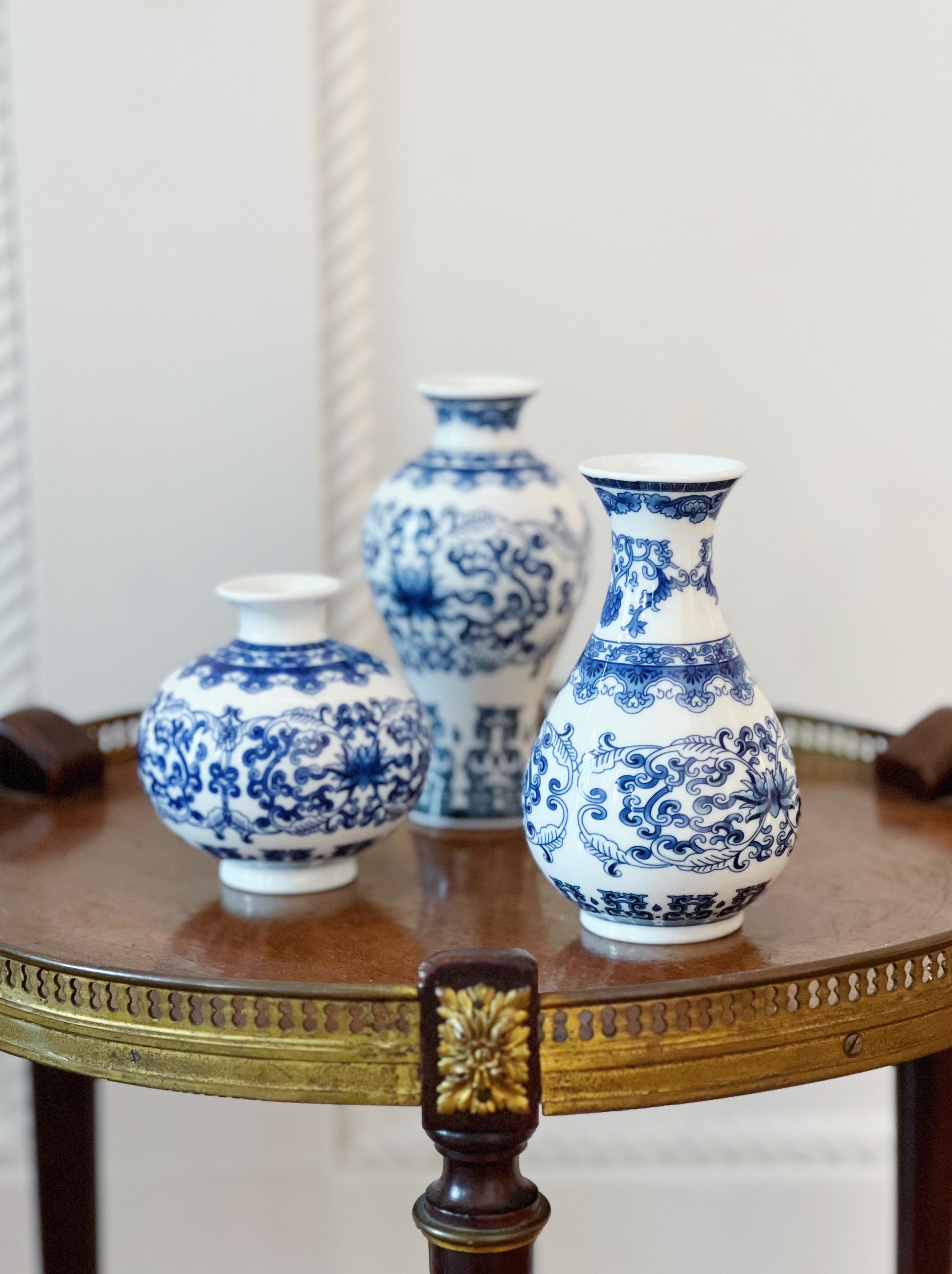 set of three blue and white bud vases on a round wooden table