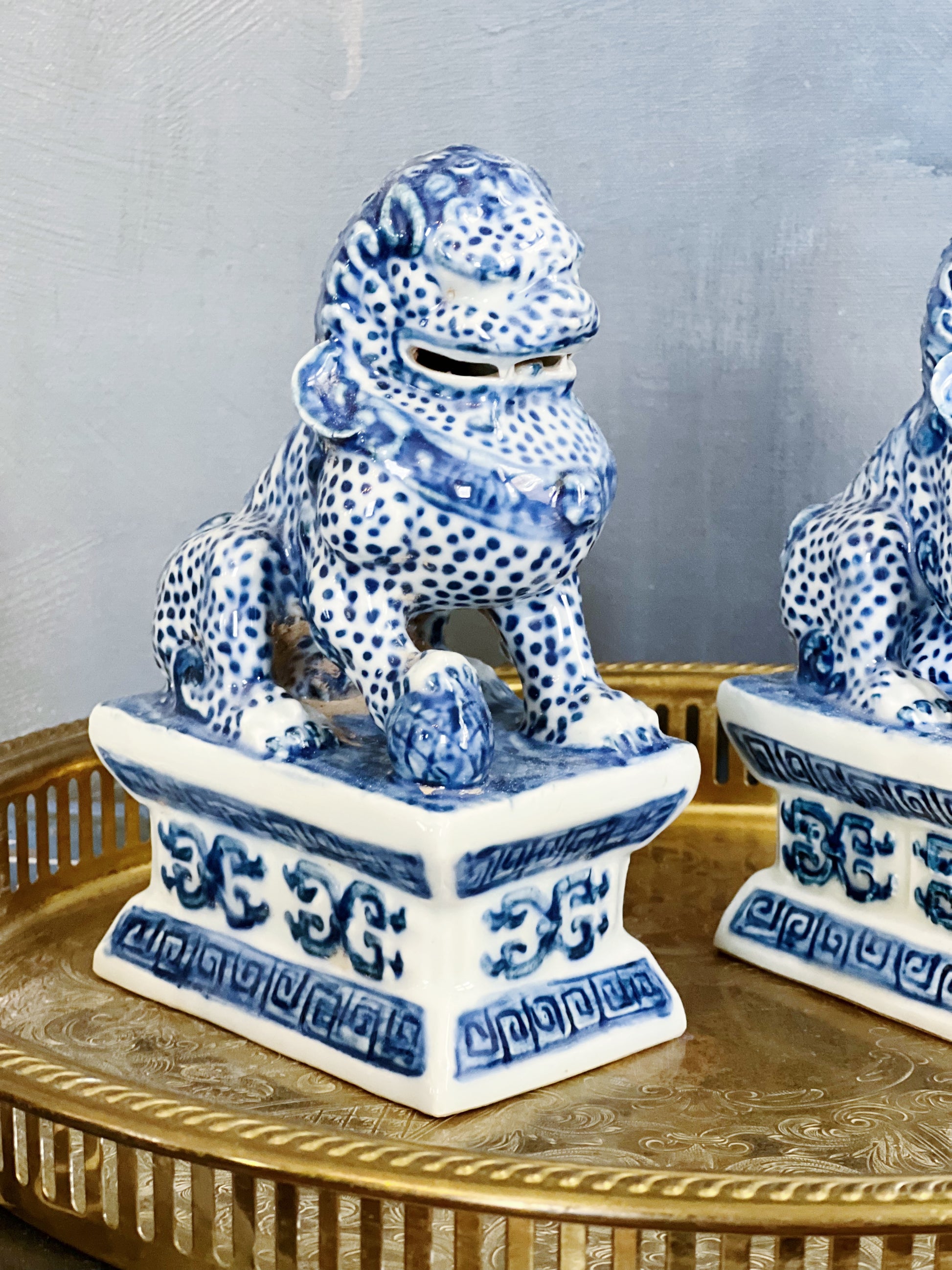 close up of blue and white foo dog set on a vintage brass serving tray