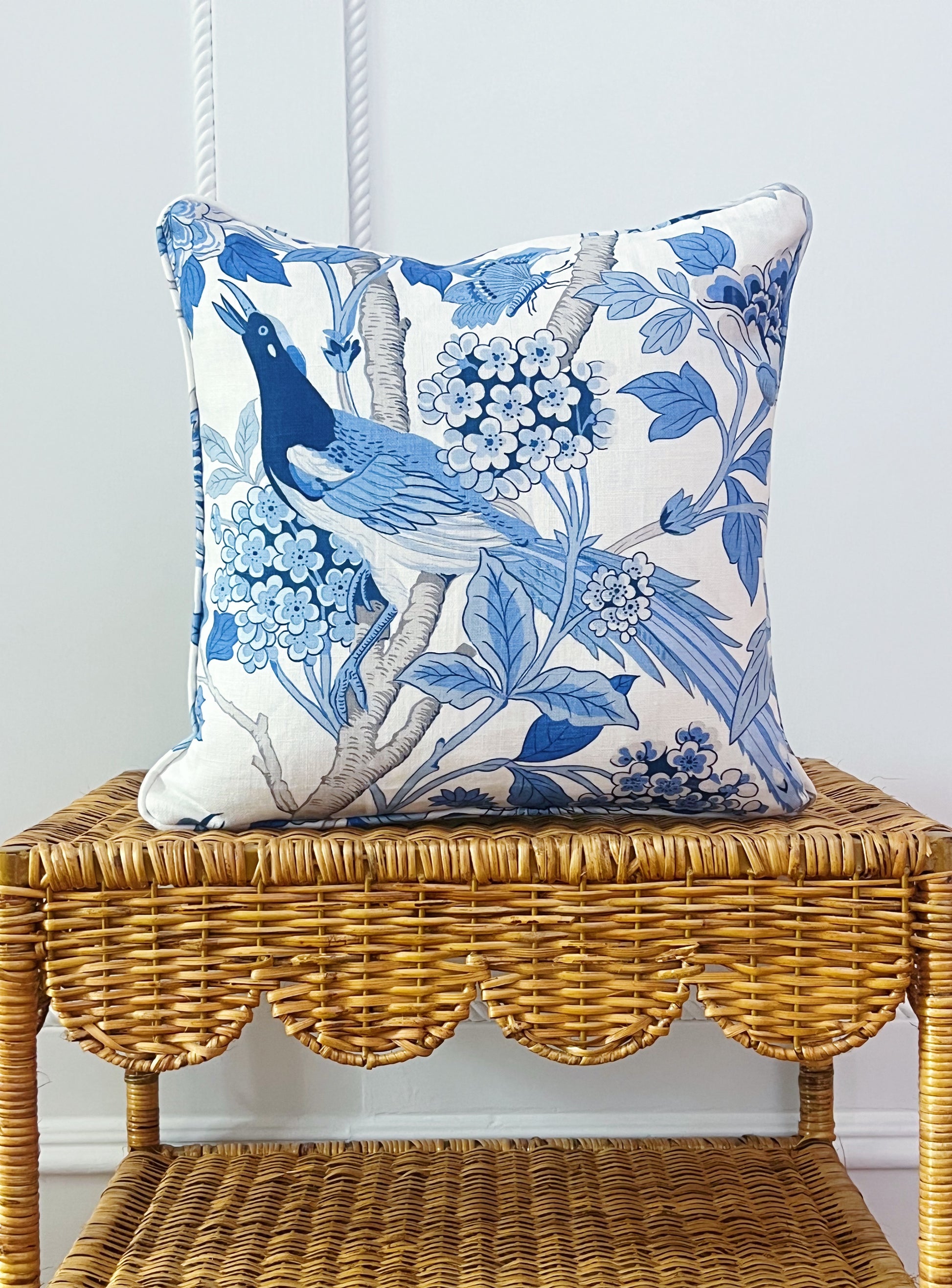 custom pillow in GP & J Baker hydrangea bird fabric on a scalloped wicker side table 